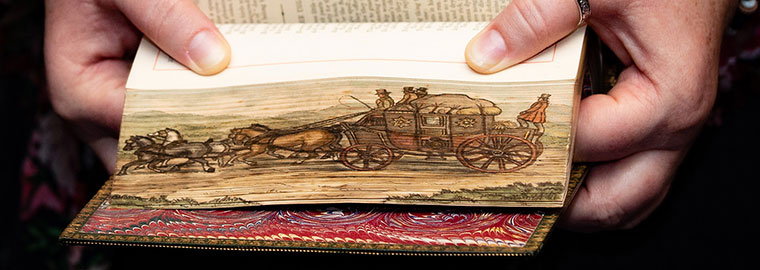 Woman holding a book showing a page edge image of horses pulling a stagecoach